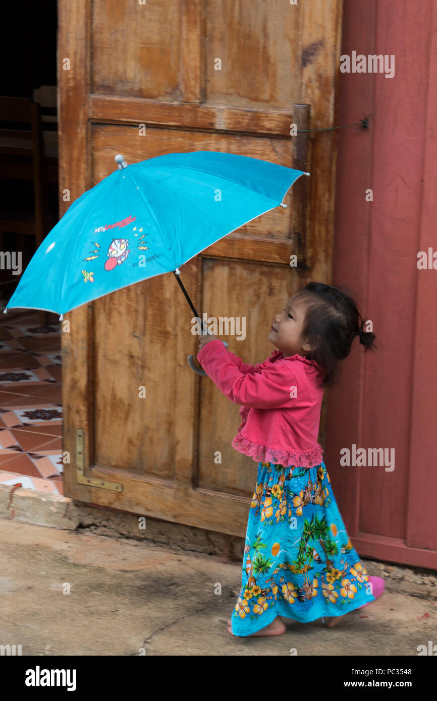 Jeune fille avec un parapluie bleu et fleuri le dresson boucle Khammouane Banque D'Images