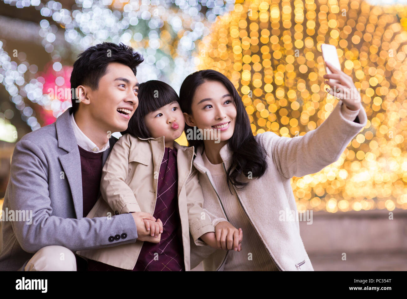 Cheerful young Chinese family taking self portrait with smart phone Banque D'Images