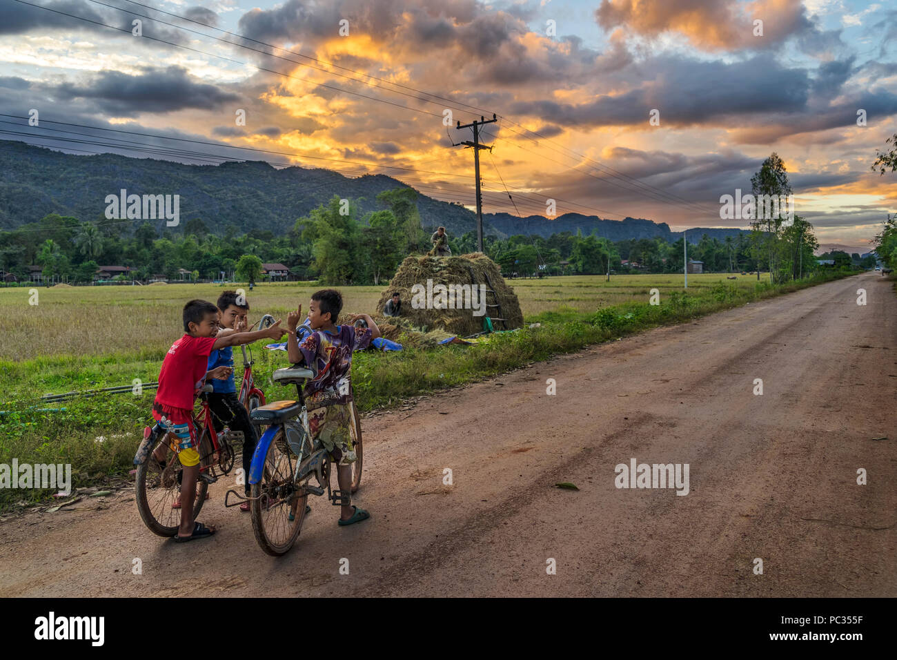 Les garçons sur des vélos sur le Kong Lor road au coucher du soleil, alors que sur la boucle de Khammouane Banque D'Images