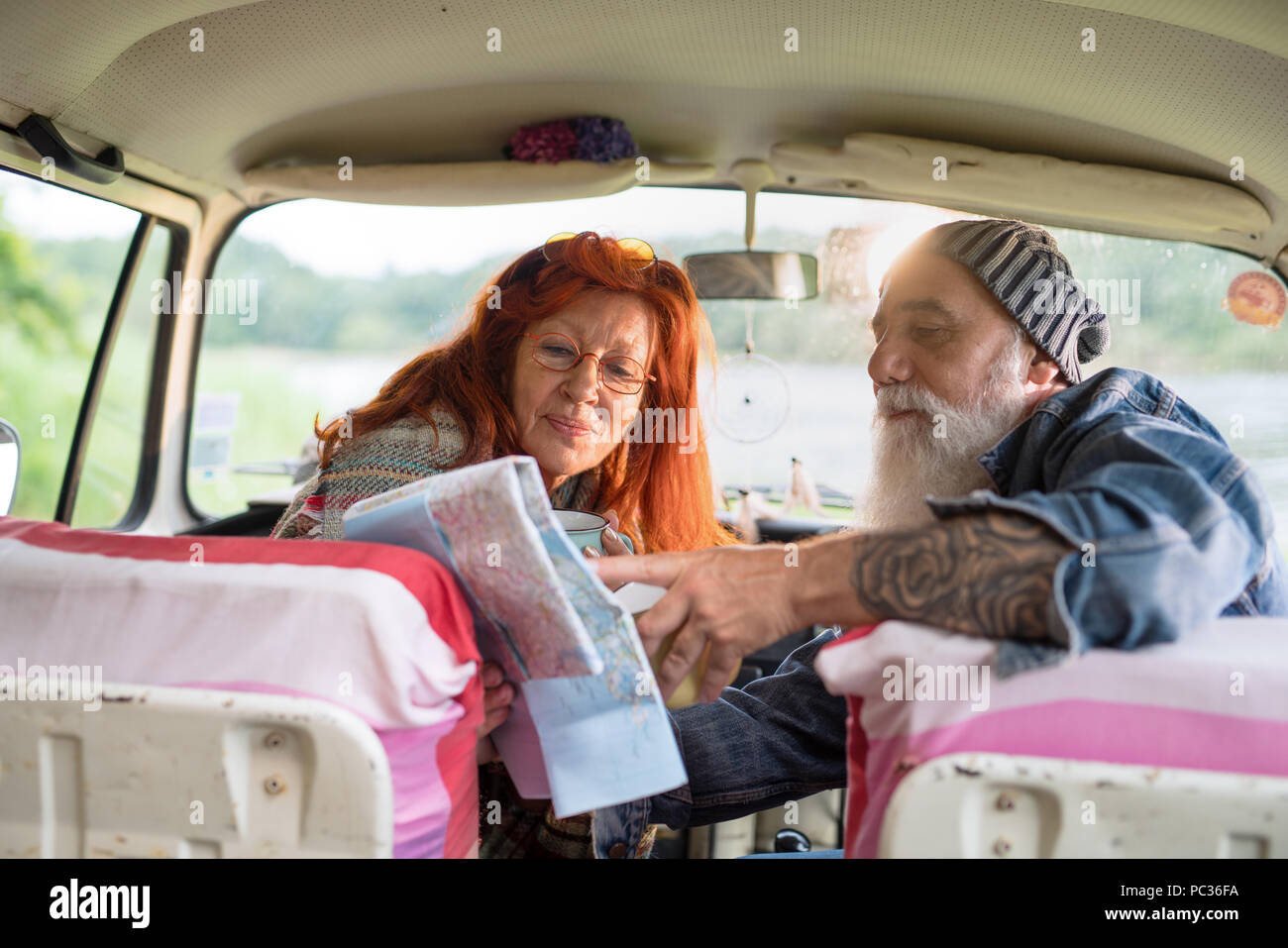 Vieux couple hipster assise dans une voiture et à la recherche à une carte routière Banque D'Images
