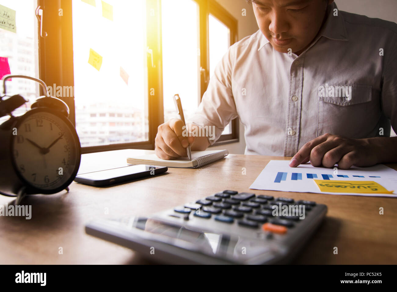 Calculer comptable finances des bénéfices annuels par appuyer sur la calculatrice et résumer l'équilibre de l'argent en écrivant sur la note book in office Banque D'Images