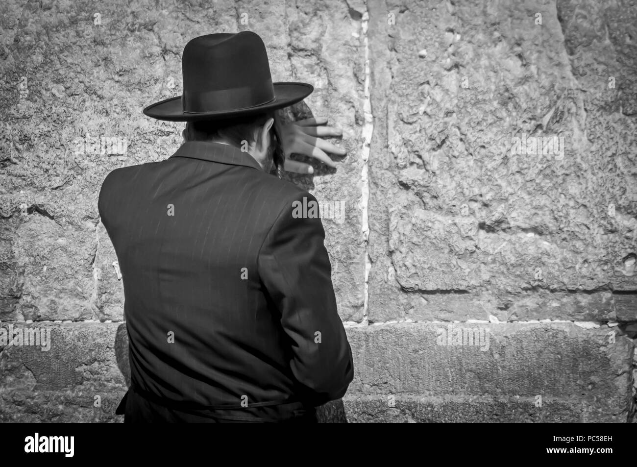 Orthodoxe juif homme priant au mur des lamentations, mur ouest concept noir et blanc de l'image. Un juif religieux dans un costume noir et chapeau noir. Banque D'Images