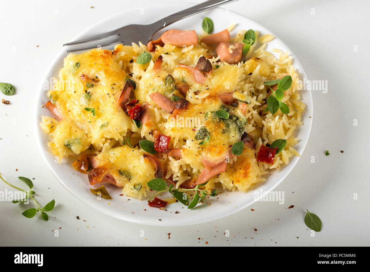 Le risotto au four avec de la mozzarella et les saucisses sur une assiette avec une fourchette Banque D'Images