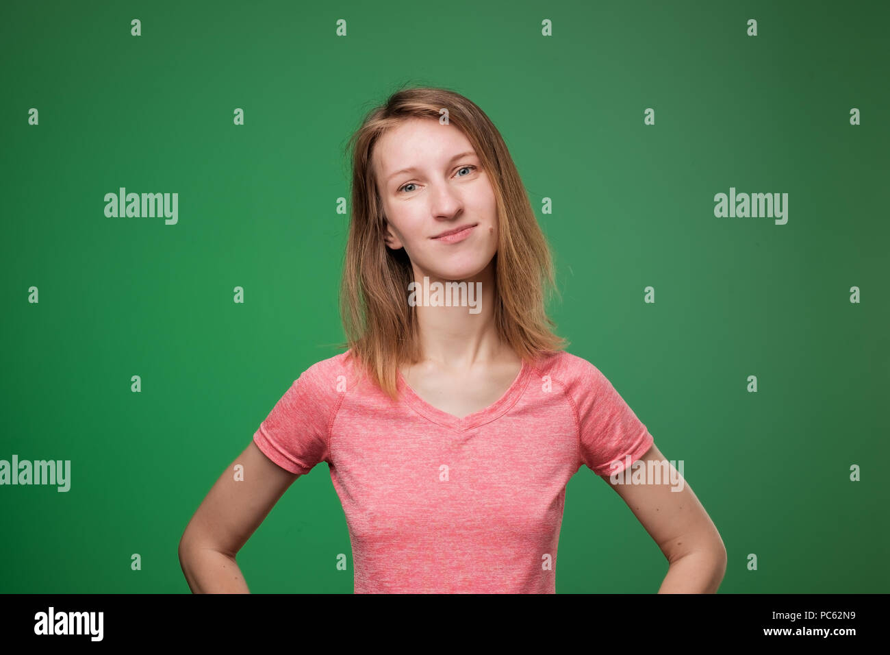 Portrait d'excité caucasian girl en t-shirt rose sur fond de couleur verte. Banque D'Images