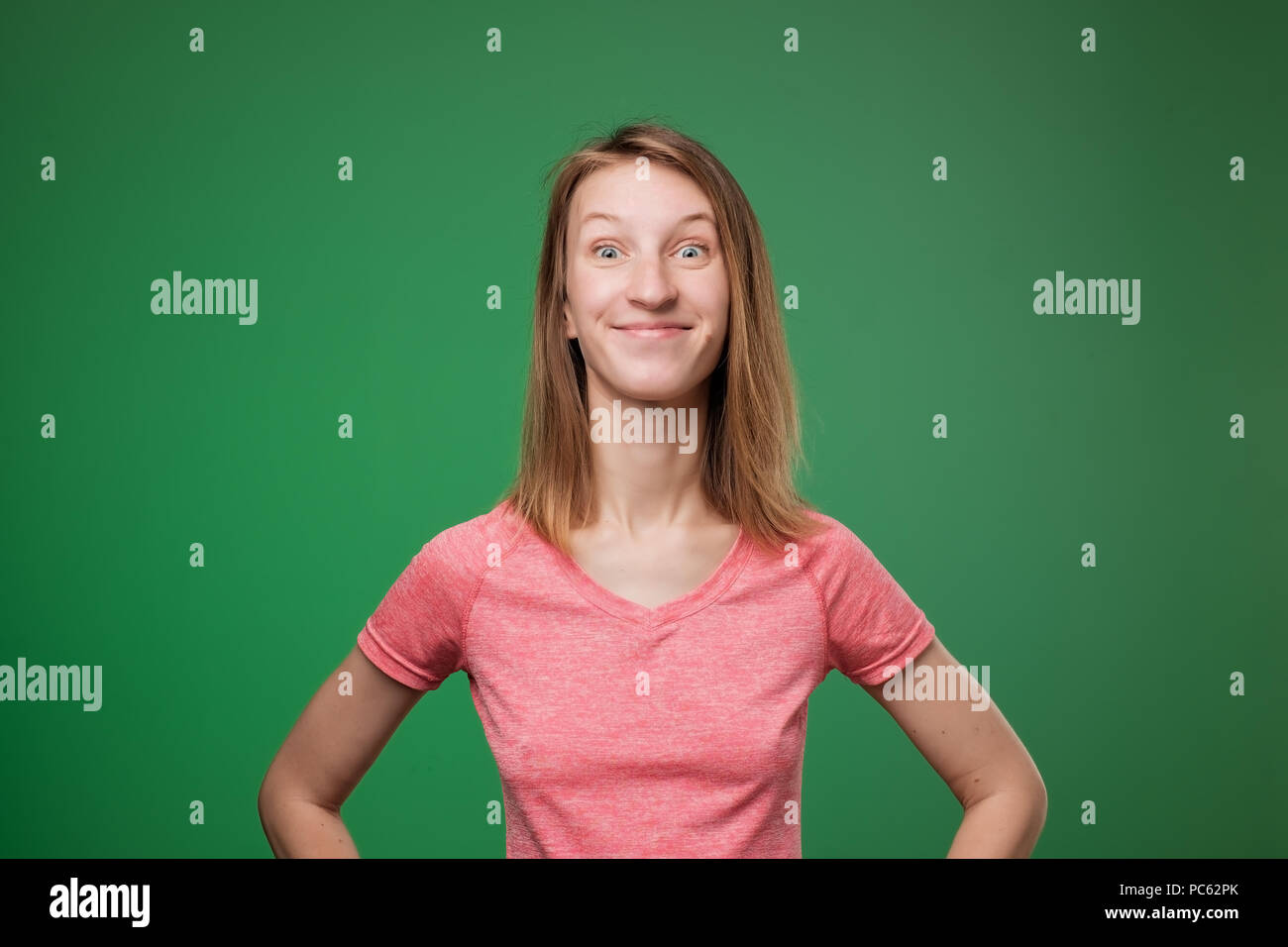 Portrait d'excité caucasian girl en t-shirt rose sur fond de couleur verte. Banque D'Images