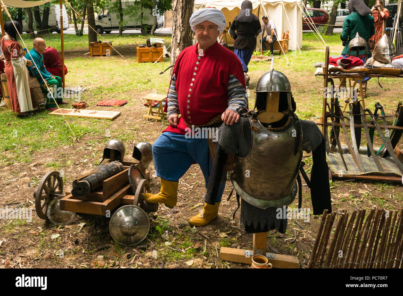 Ploiesti, Roumanie - 14 juillet 2018 : l'acteur habillé guerrier turc ottoman pose entouré d'armes médiévales, cannon, épées et armures du corps et de la tête Banque D'Images