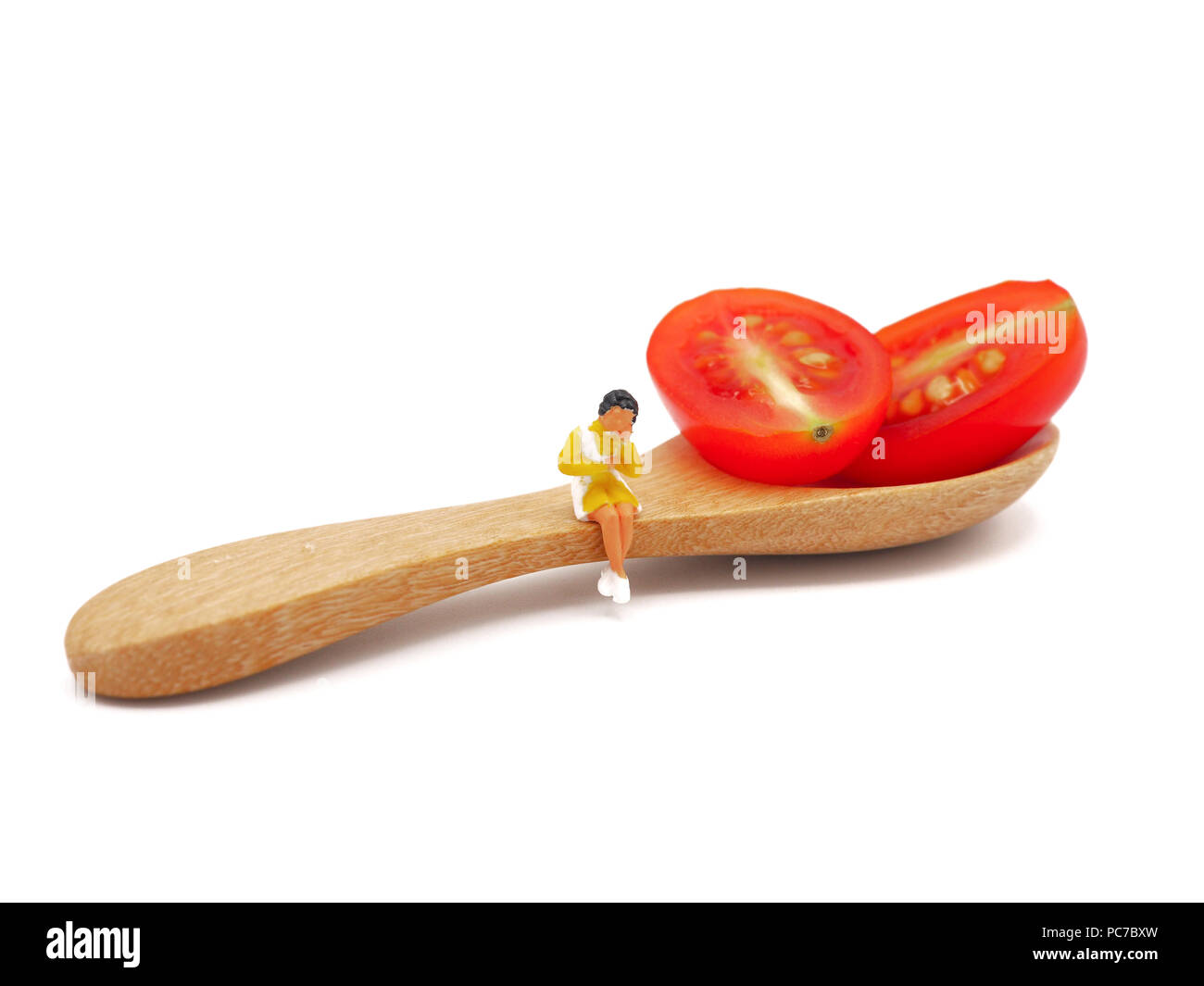 Femme assise sur miniature ou de raisin frais tomate cerise avec une cuillère de bois, la pensée de la perte de poids et de corps mince. Concept de vie sain bac blanc. Banque D'Images