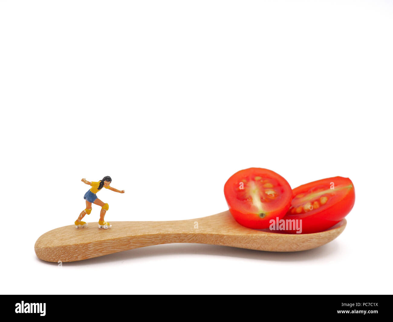 Femme miniature patinage sur tomate cerise raisin frais ou avec une cuillère de bois, la pensée de la perte de poids et de corps mince. Concept de vie sain bac blanc. Banque D'Images