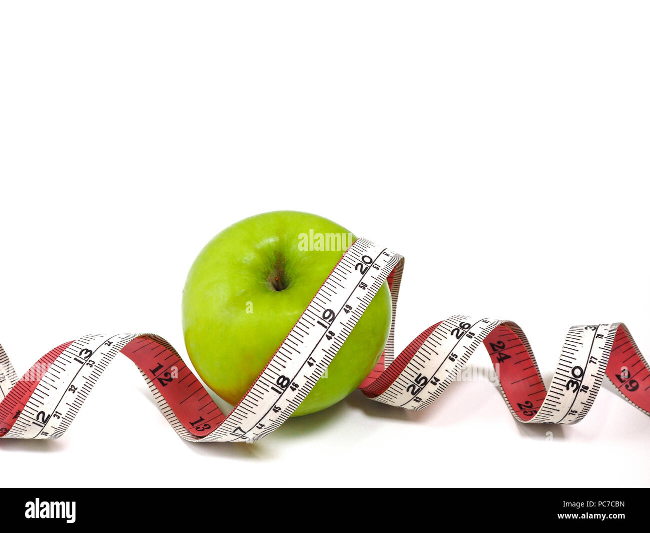 Ruban à mesurer et de pomme verte sur fond blanc. Concept de vie et d'aliments sains. Banque D'Images