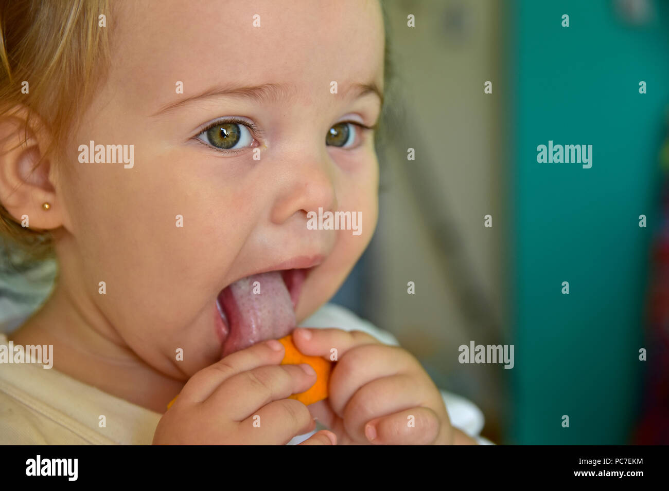 Baby Girl eating orange pour la première fois. Montrant ses réactions drôles alors qu'elle goûte les fruits. Banque D'Images