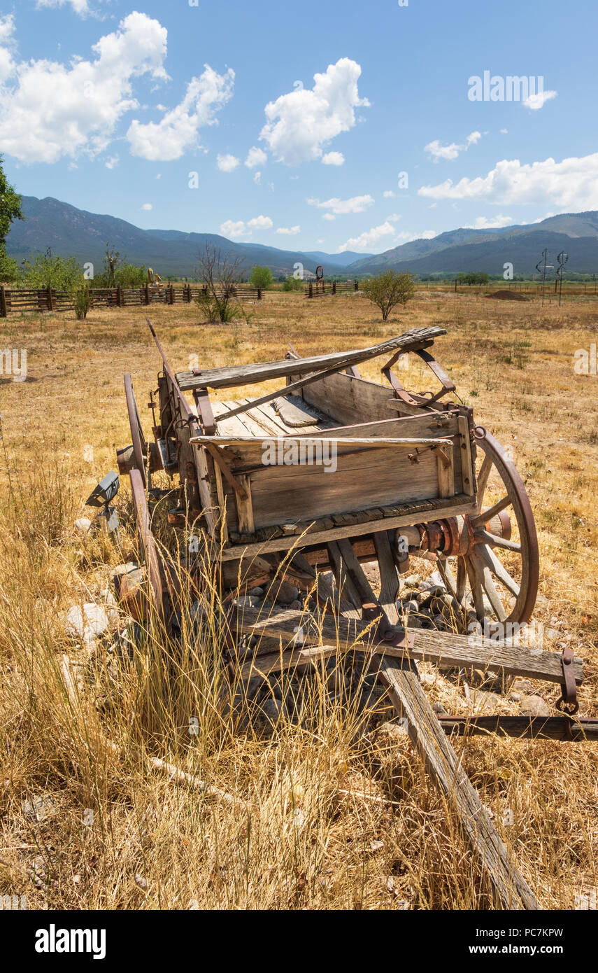TAOS, NM, USA-8 le 18 juillet : une ancienne, détérioration de wagon avec des rayons en bois et métal jantes se trouve abandonné dans un champ à côté d'Overland Ranch de mouton. Banque D'Images