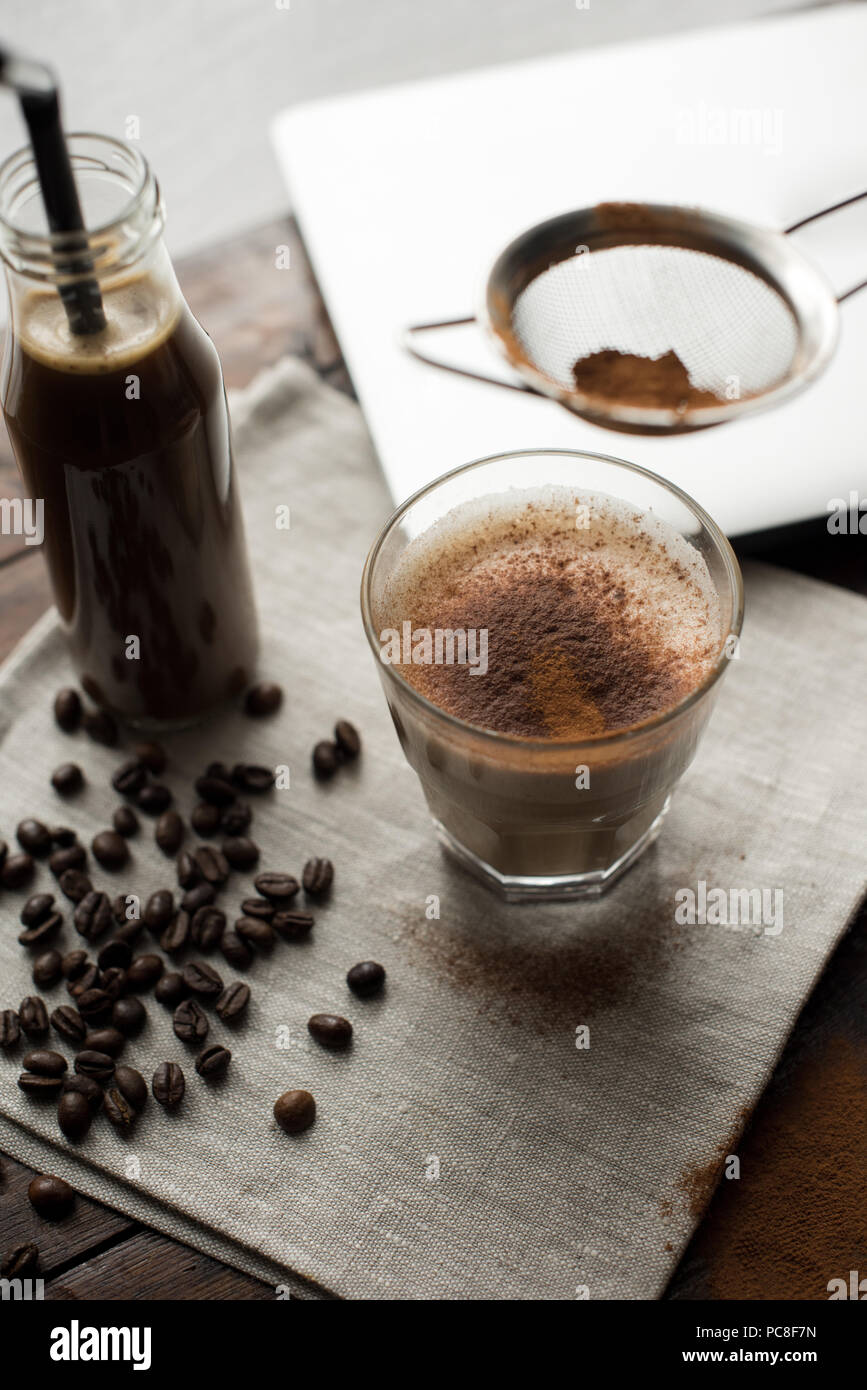 Bocal de café verre avec tube en verre et d'un cappuccino avec du cacao en  poudre sur les grains de café avec serviette Photo Stock - Alamy