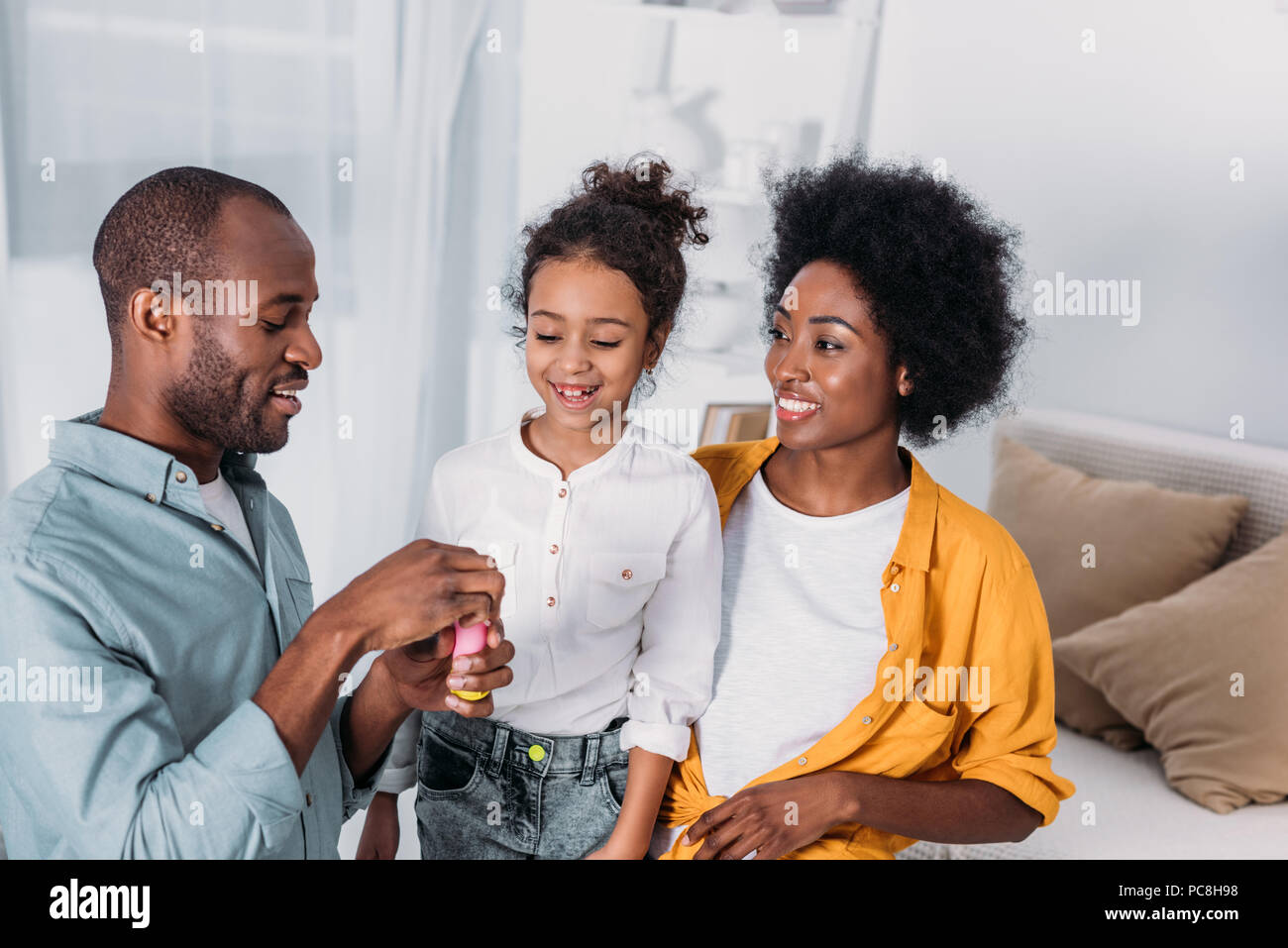 Les parents afro-américain et sa fille faisant des bulles de savon à la maison Banque D'Images