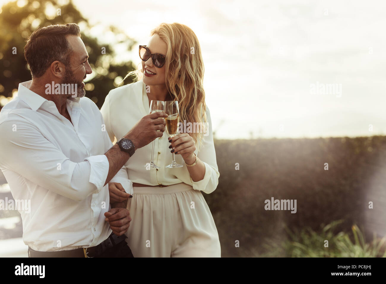 Romantic couple toasting verres à vin à l'extérieur. Belle femme de trinquer le verre de vin avec son petit ami. Banque D'Images