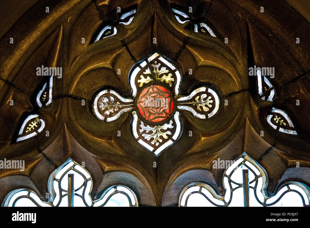 Une rose rouge de verre décoratif fenêtre dans un châssis de grès à John Rylands Library, Manchester, UK Banque D'Images