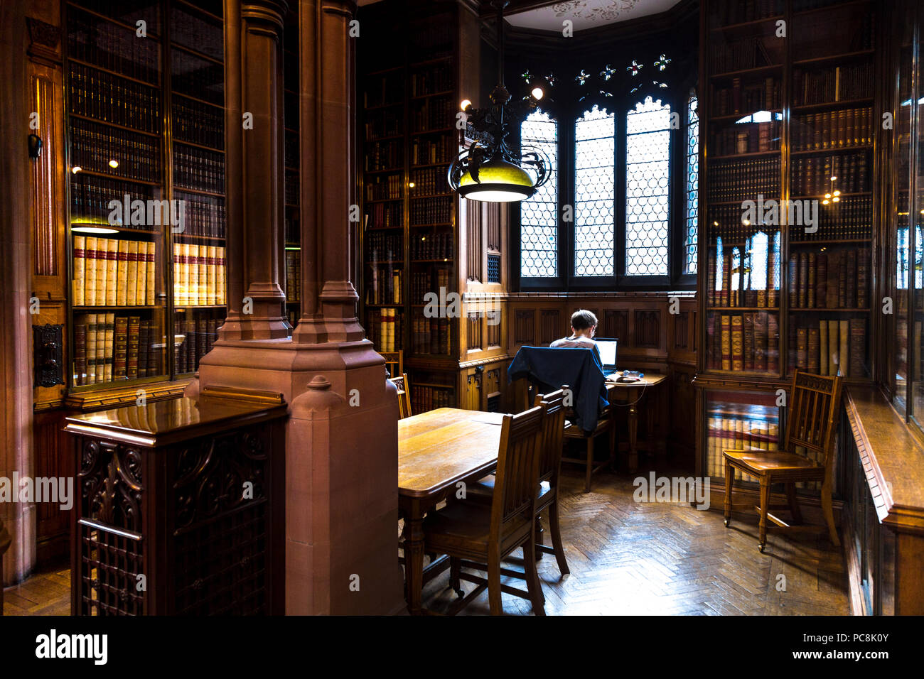Homme assis avec un ordinateur portable à une vieille bibliothèque faire des recherches, étudier, Johny Rylands Library, Manchester, UK Banque D'Images