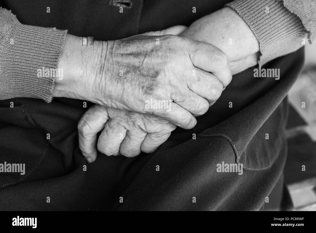 Mains d'une vieille femme sur ses genoux - noir et blanc, selective focus Banque D'Images
