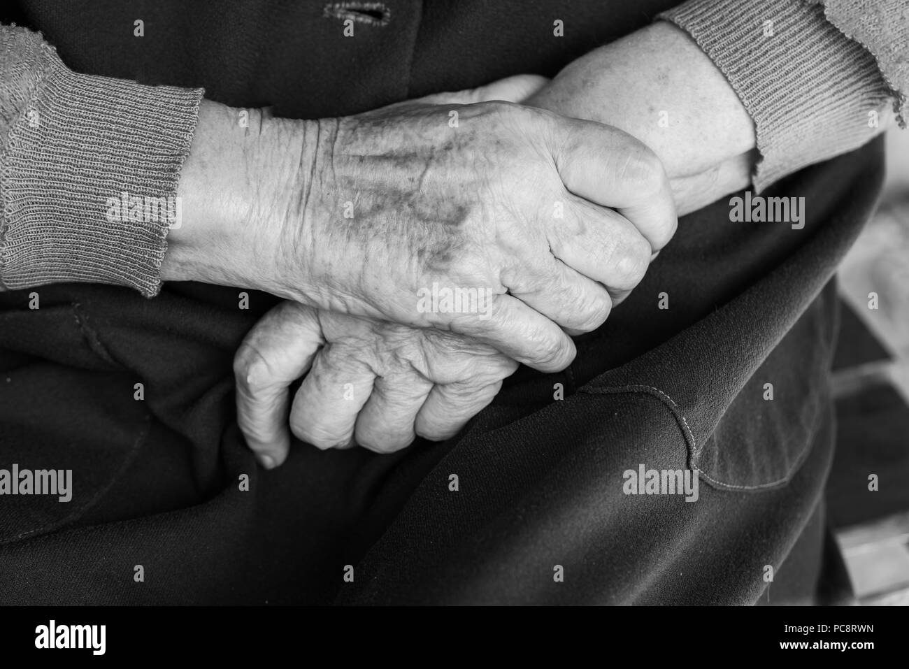 Mains d'une vieille femme sur ses genoux - noir et blanc, selective focus Banque D'Images