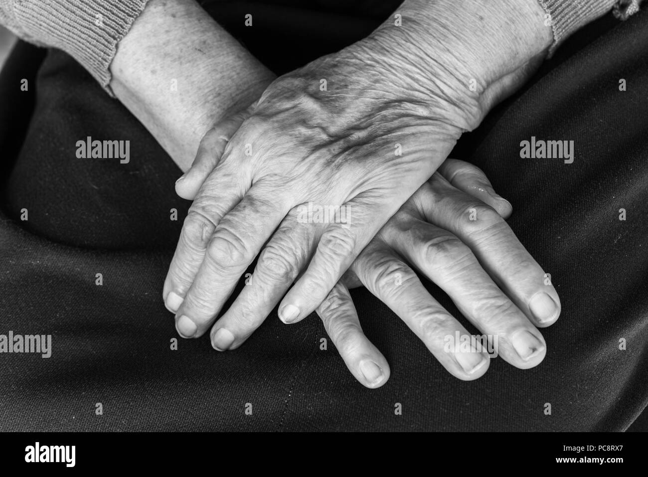 Mains d'une vieille femme sur ses genoux - noir et blanc, selective focus Banque D'Images