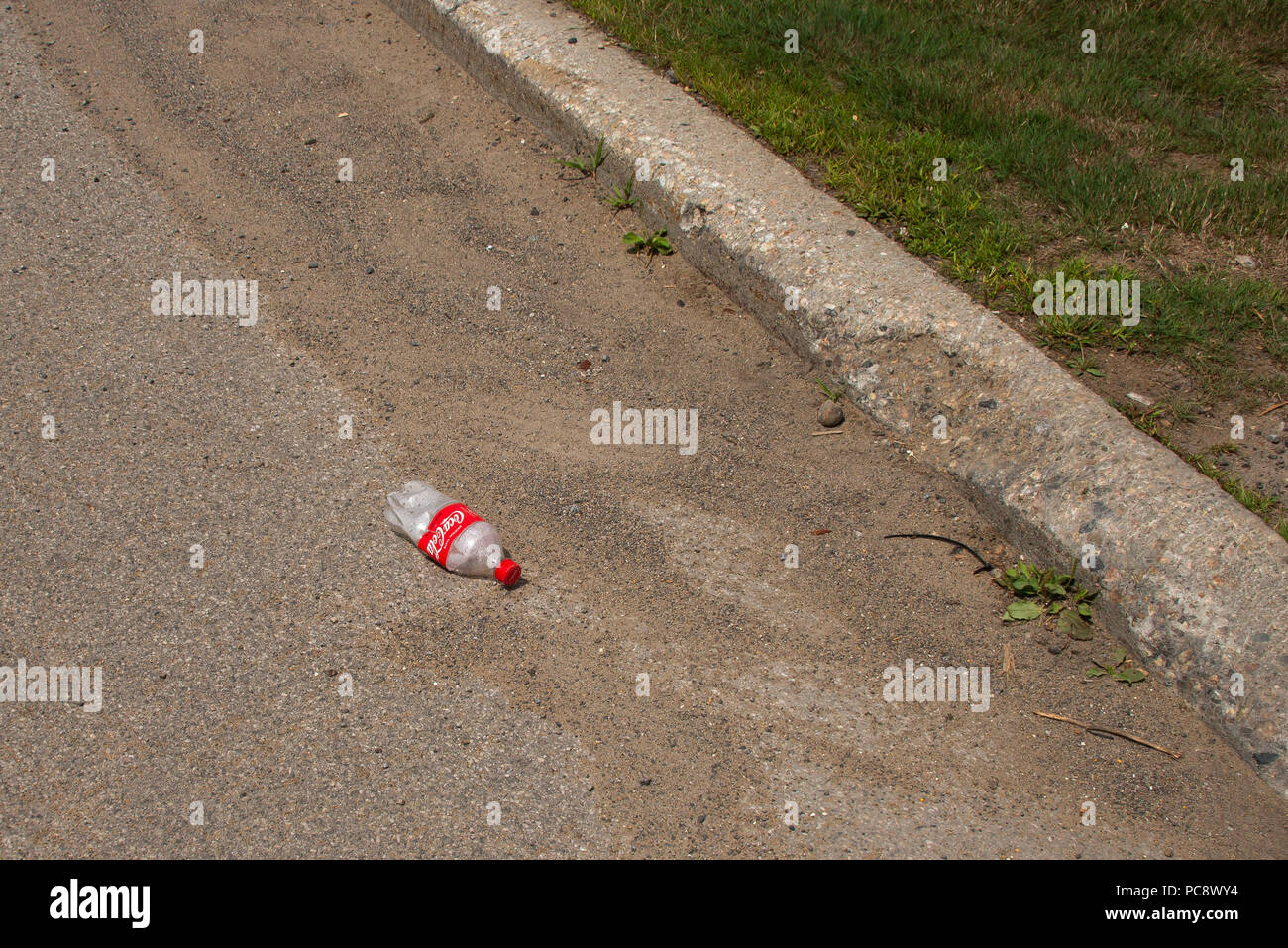 Une bouteille vide jetée située dans la rue ou dans des gouttières spéculateur, NY USA, litière concept. Banque D'Images