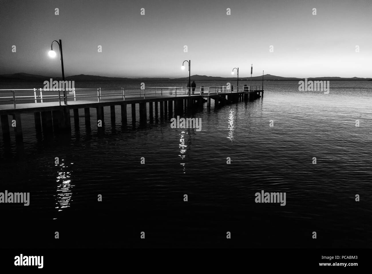 Certaines personnes sur un quai au lac Trasimeno (Ombrie, Italie) au crépuscule Banque D'Images