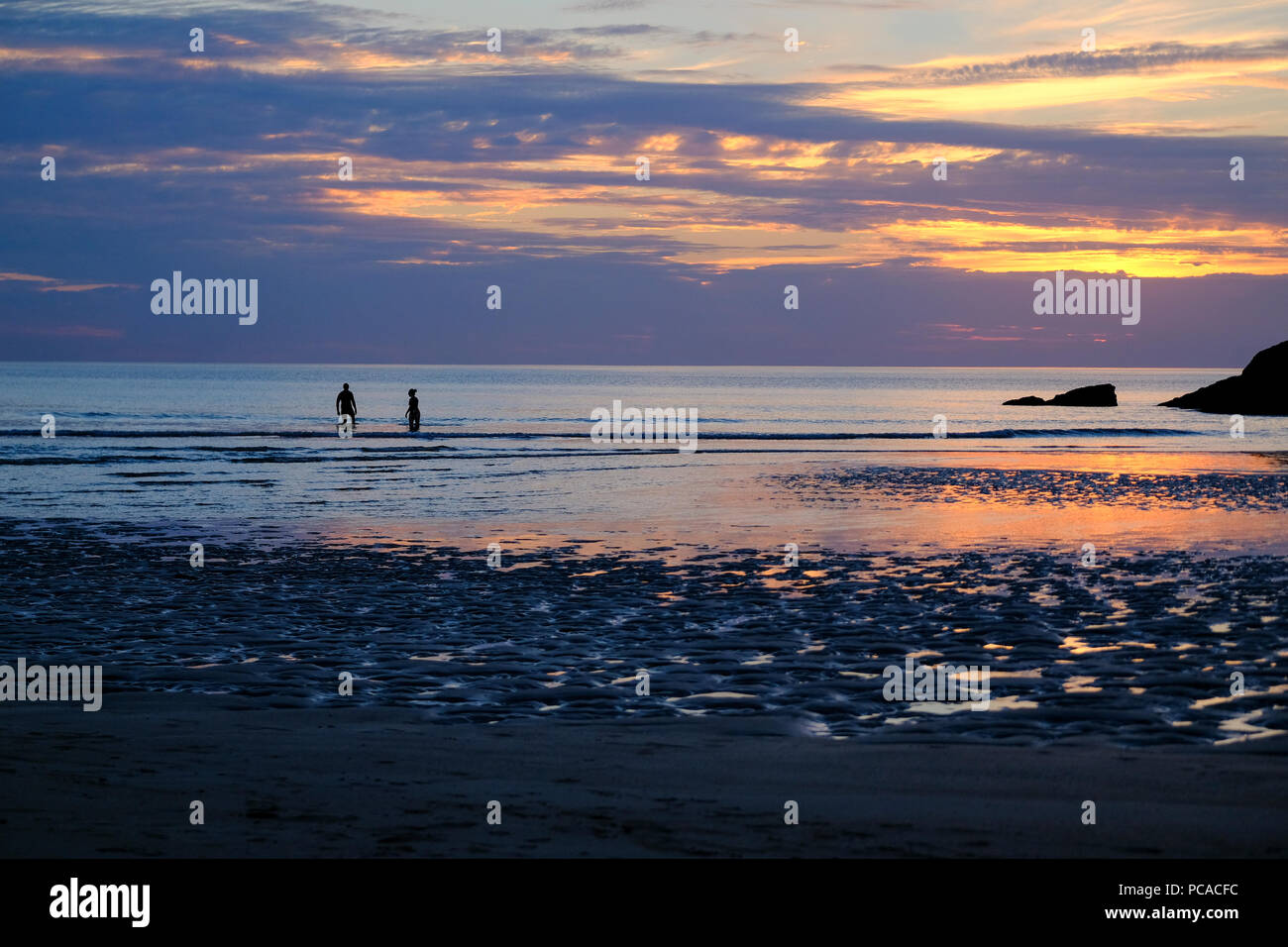 Couple en train de marcher sur la plage de Porth Newquay Cornwall au en au coucher du soleil Banque D'Images