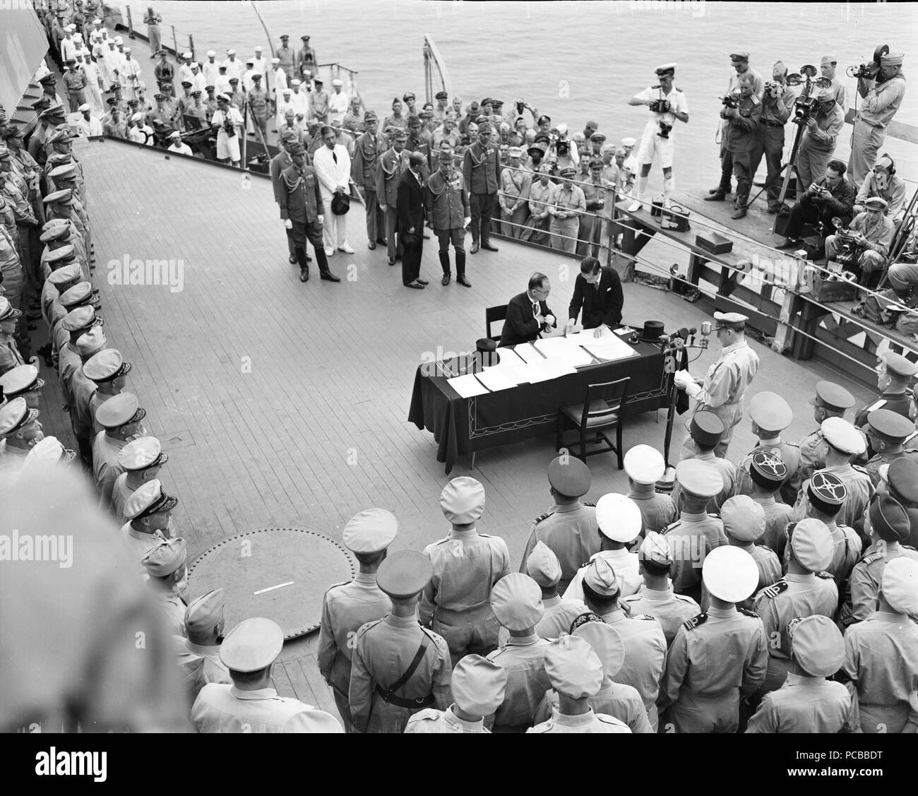 La Seconde Guerre mondiale photo - cérémonie de remise sur l'USS Missouri (BB-63) La baie de Tokyo. Le ministre japonais des affaires étrangères, Namoru Shigemitsu, signe les termes de la reddition comme officiers alliés regardez le 2 septembre 1945. Banque D'Images