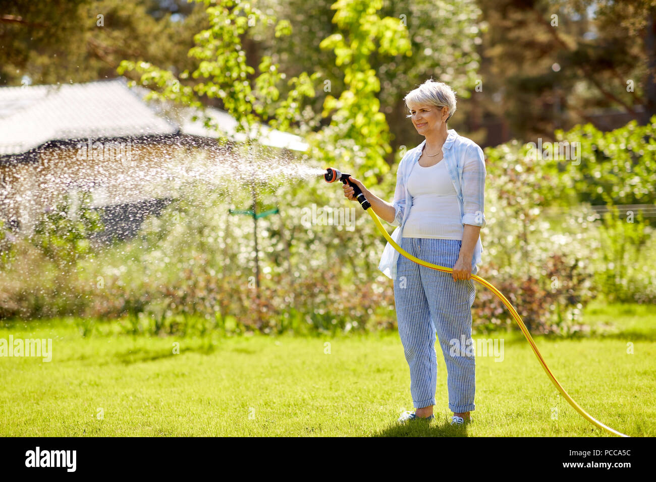 Woman watering grass with hose Banque de photographies et d'images à haute  résolution - Alamy