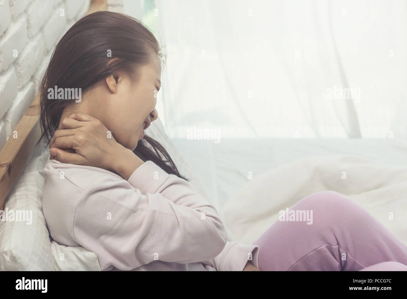 Femme Asiatique d'une douleur au cou après service de réveil matin dans le lit dans la chambre Banque D'Images