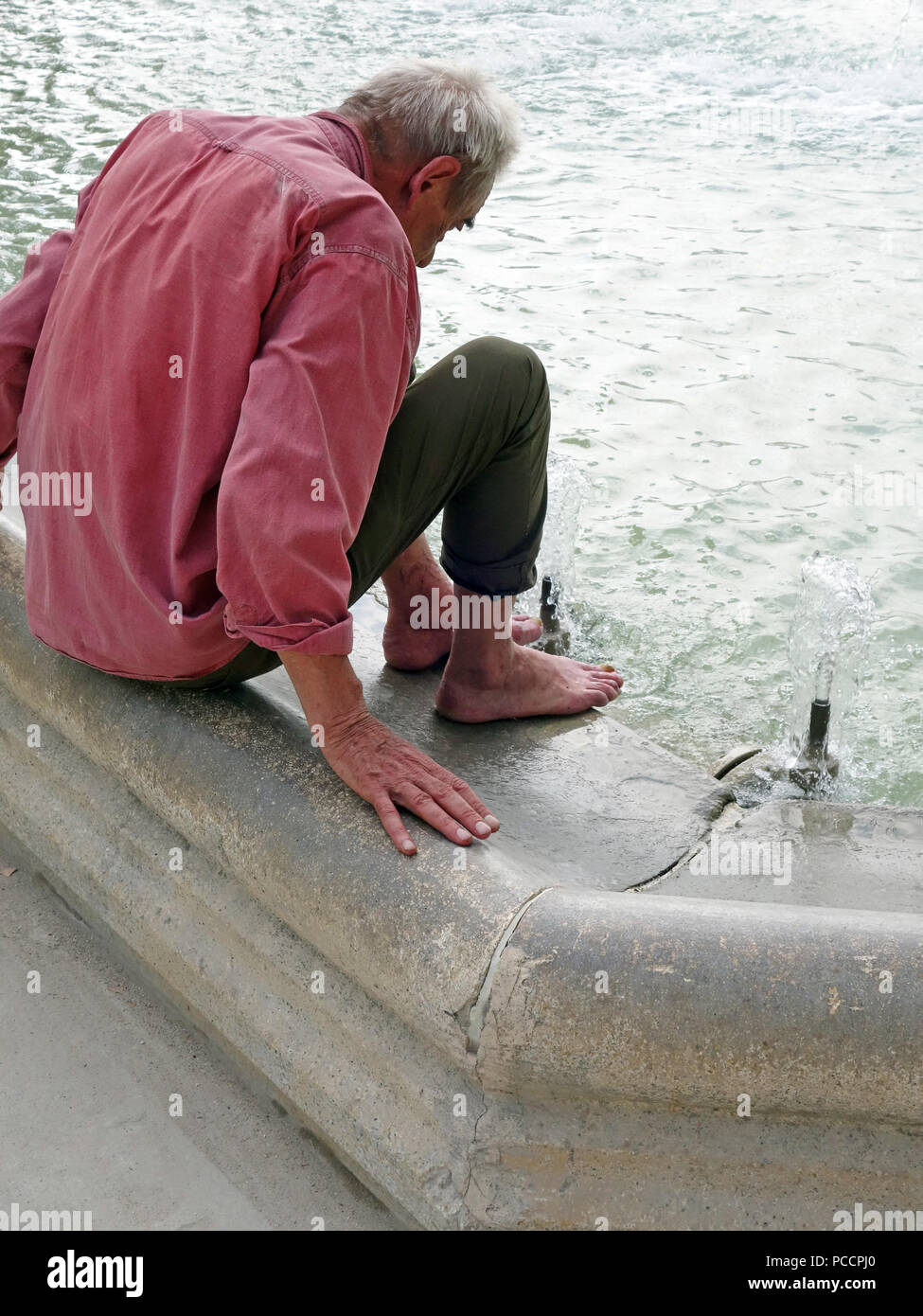 Vieil Homme Avoir Chaud Et Inconfortable Dans La Canicule Tente De Se Rafraichir En Mettant Ses Pieds Dans La Fraicheur De L Eau De La Fontaine Photo Stock Alamy