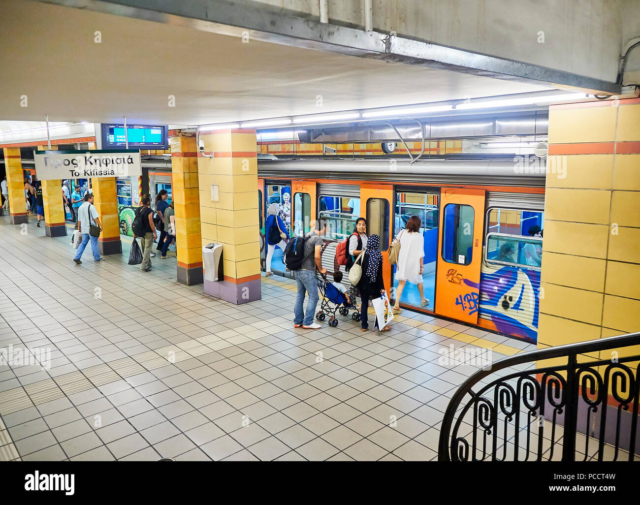 Les personnes prenant un train peint avec des graffitis dans une station de métro d'Athènes. Banque D'Images