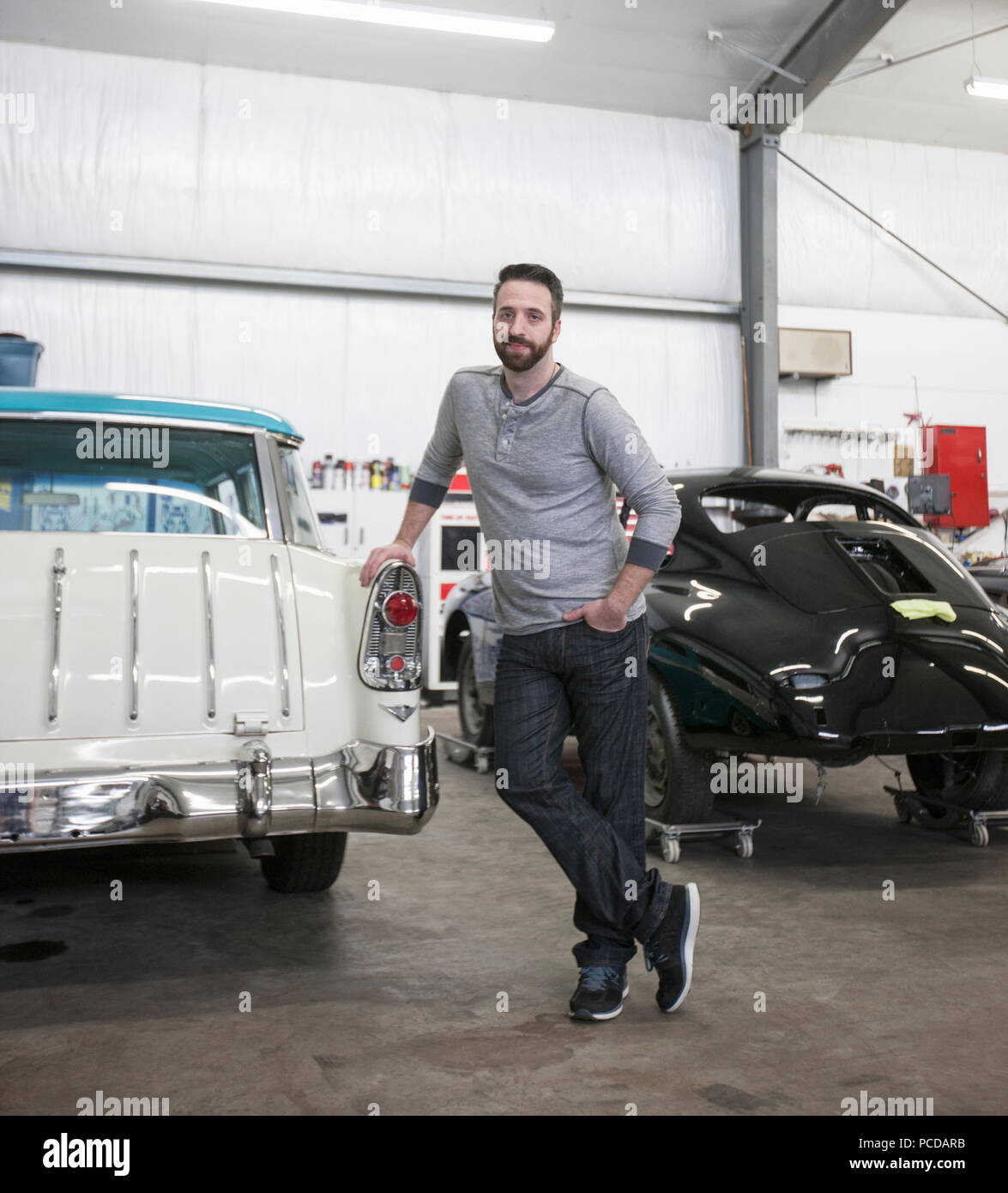 Un portrait d'un mécanicien de race blanche dans son atelier de réparation de voitures classiques. Banque D'Images