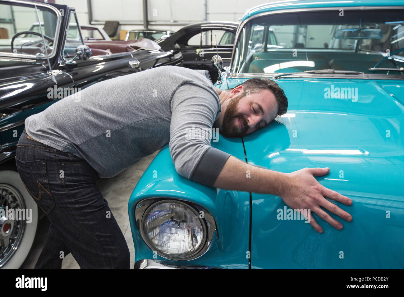 Un homme de race blanche serrant le capot de son vieux sedan dans une voiture classique atelier de réparation. Banque D'Images