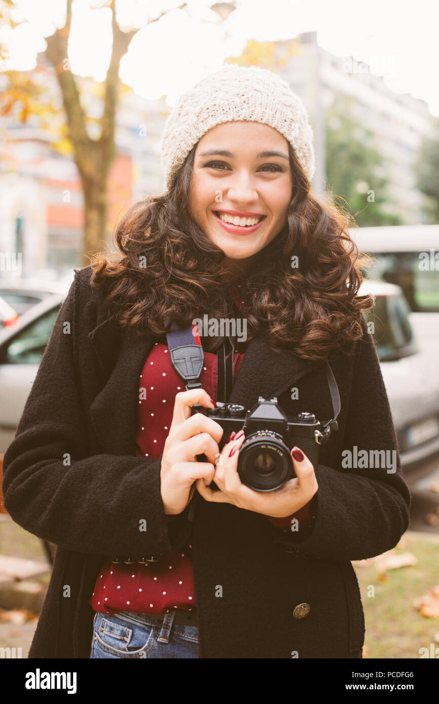 Belle jeune femme avec un bonnet de prendre des photos avec un appareil  photo rétro dans la ville à l'automne Photo Stock - Alamy