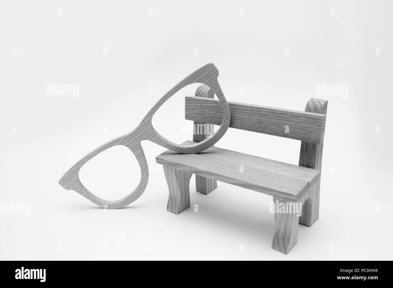 Concept de la vieillesse, maquette en bois banc avec lunettes en bois sur un fond blanc, la sagesse, la contemplation, hipsters Banque D'Images
