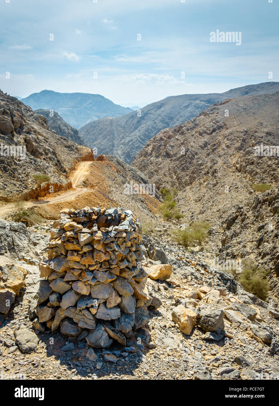 Route de terre à Al Hajar mountains à FUJAIRAH, EMIRATS ARABES UNIS avec une pyramide de roche au premier plan Banque D'Images