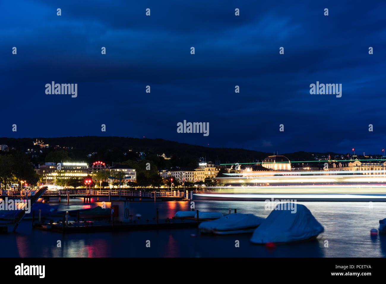 Grand bateau de croisière sur le lac de Zurich dans la nuit avec de l'eau et l'éclairage bleu ciel nuageux Banque D'Images