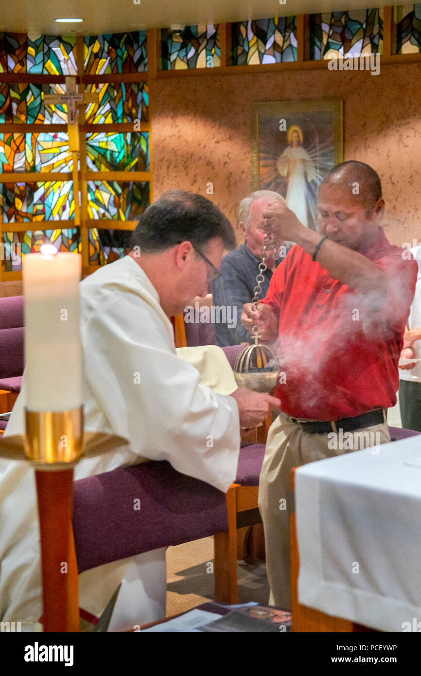 Avec l'aide d'un paroissien vietnamiens, un diacre robed'allume brûleur d'encens au début d'une miséricorde divine et la bénédiction du service dans la chapelle d'un Laguna Niguel, CA, l'église catholique. Banque D'Images