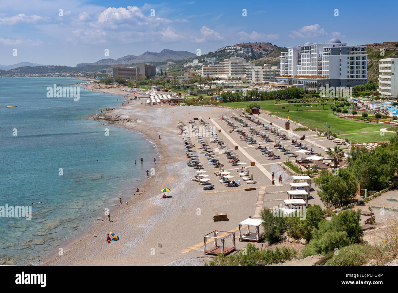 Des chaises longues avec parasols sur la plage de sable de Faliraki. L'île de Rhodes, Dodécanèse, Grèce. Banque D'Images