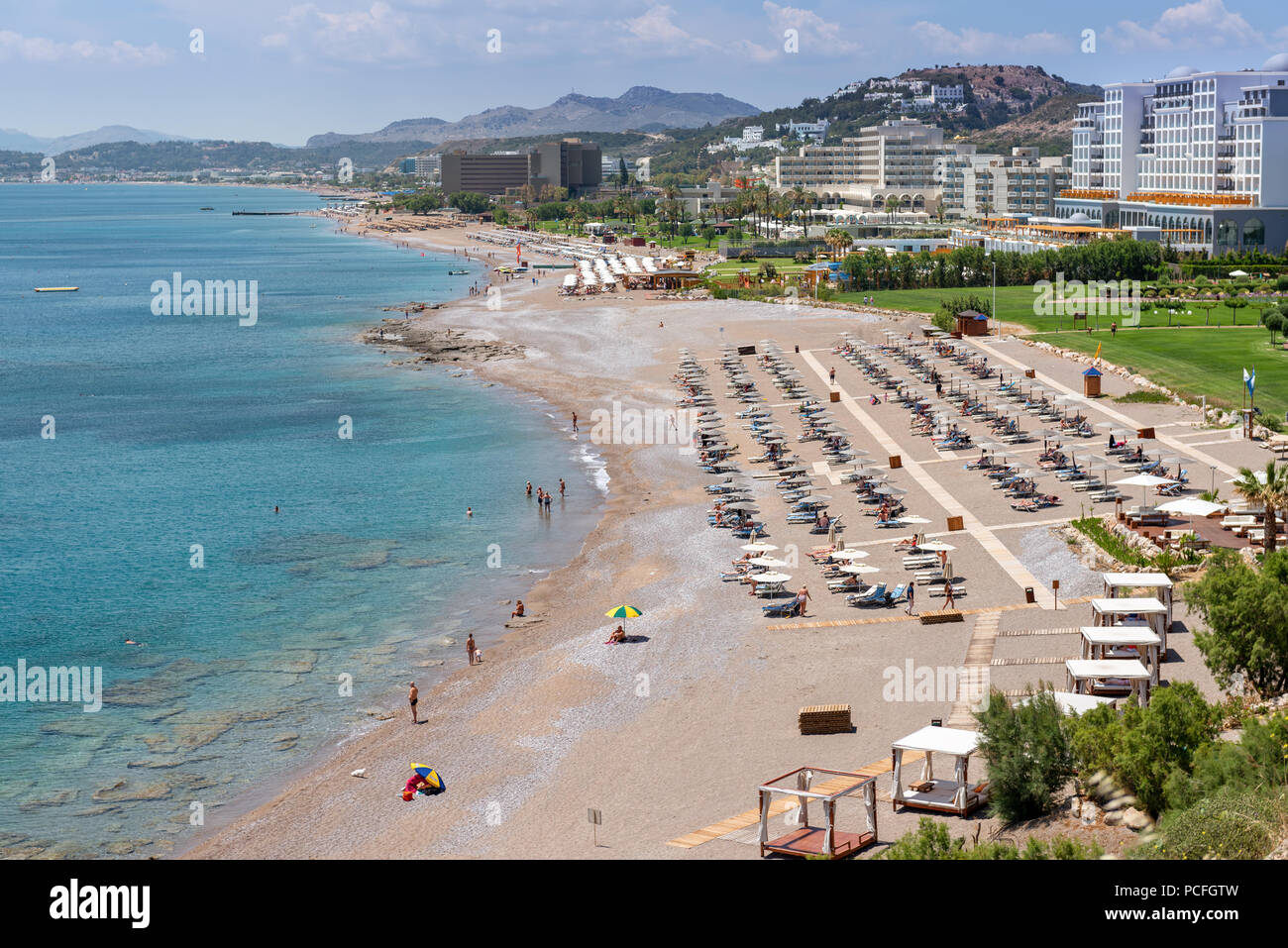 Des chaises longues avec parasols sur la plage de sable de Faliraki. L'île de Rhodes, Dodécanèse, Grèce. Banque D'Images