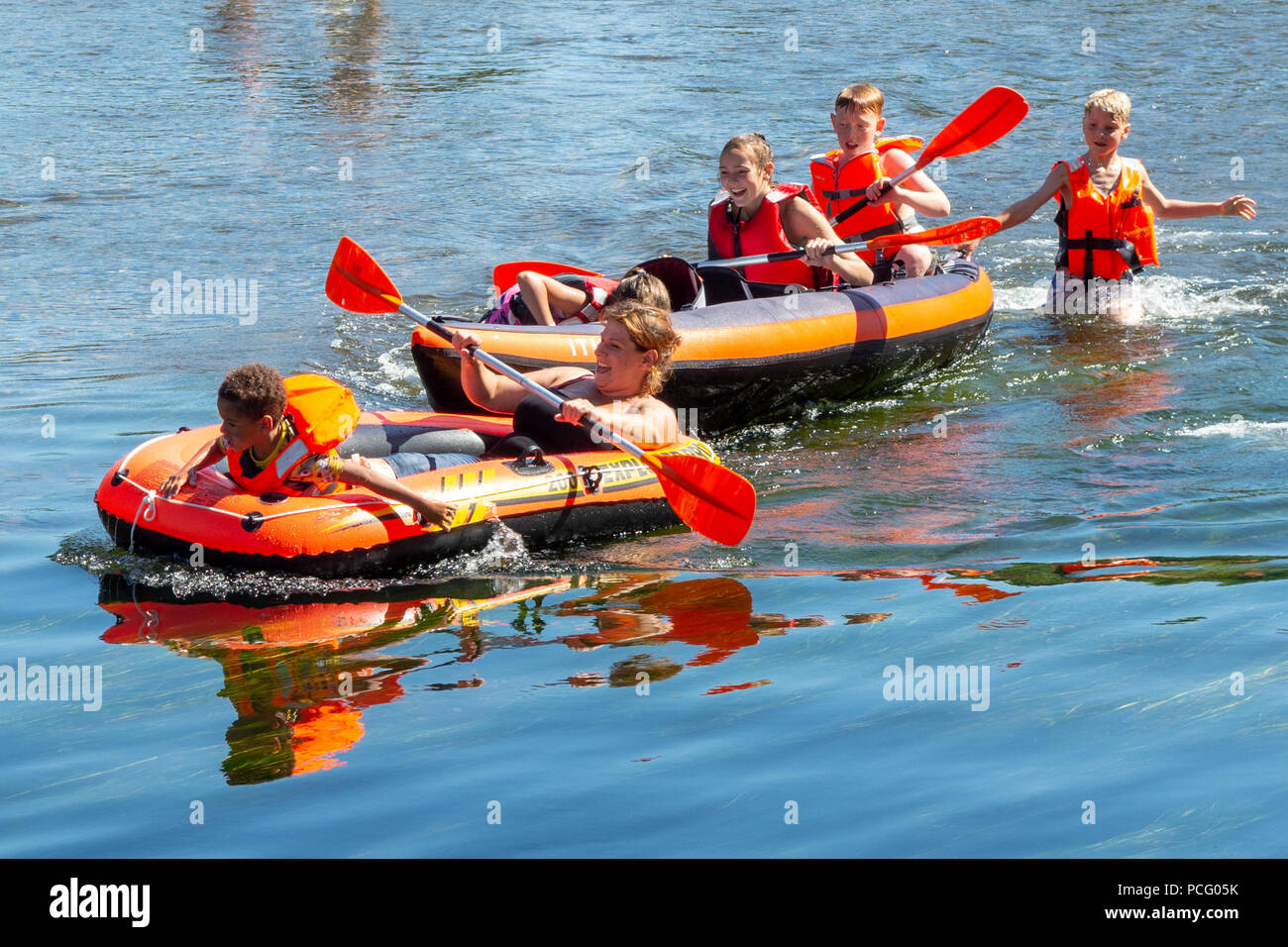 Enfants jouant à bord d'un canot pneumatique sur une rivière par temps chaud, Royaume-Uni Banque D'Images