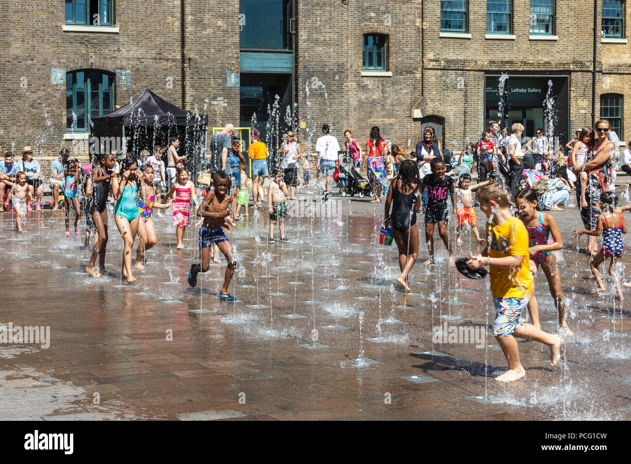 Les familles et les enfants se rafraîchissent dans les fontaines de Granary Square tandis que les températures montent, King's Cross, Londres, Royaume-Uni Banque D'Images