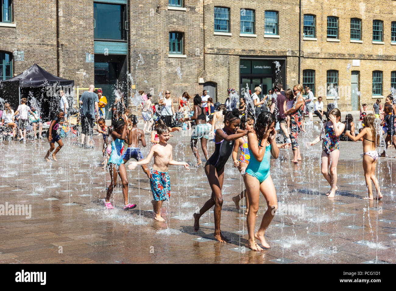 Les familles et les enfants se rafraîchissent dans les fontaines de Granary Square tandis que les températures montent, King's Cross, Londres, Royaume-Uni Banque D'Images