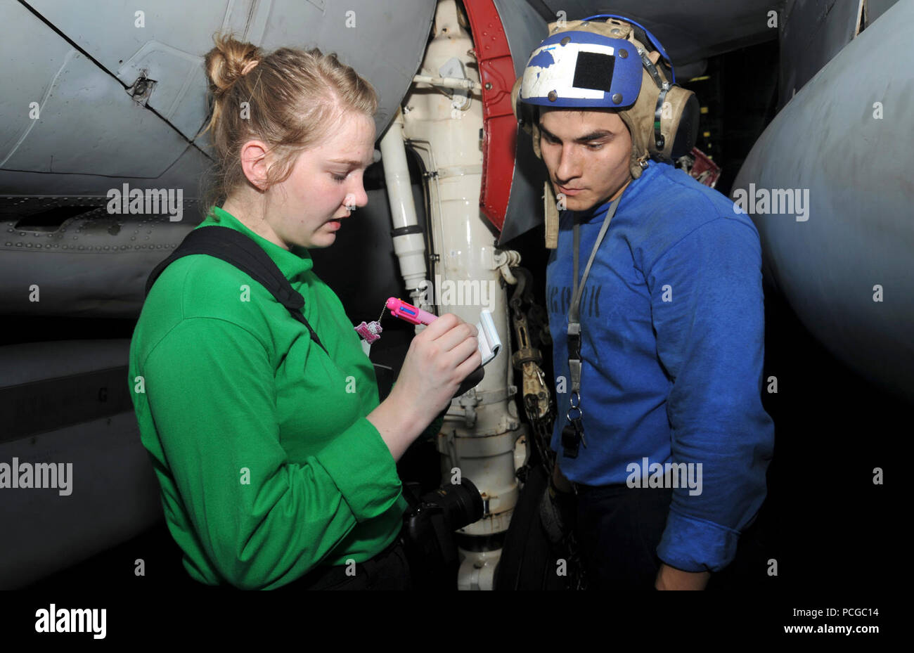 La Marine américaine spécialiste de la communication de masse 3 Classe Vandergriend Lorelei, gauche, prend les légendes les provenant de l'Aviation maître de Manœuvre (manutention) Airman Recruter des eaux de Brandon à bord du porte-avions USS George H. W. Bush (CVN 77) dans le golfe Persique le 7 juillet 2014. Le George H. W. Bush était d'appuyer les opérations de sécurité maritime et les efforts de coopération en matière de sécurité dans le théâtre dans la 5e Flotte des États-Unis zone de responsabilité. Banque D'Images