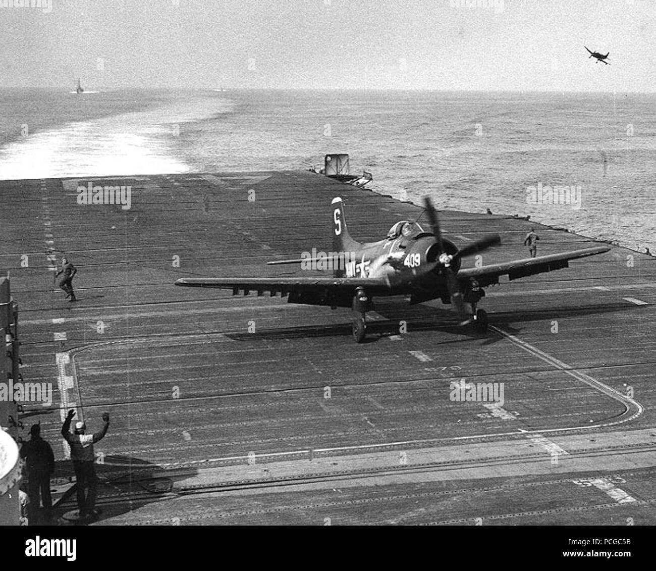 USS Valley Forge (CVA-45) : Commandant C.V. Johnson de l'avant après avoir fait les taxis du transporteur 50 000e l'atterrissage, au cours d'opérations au large de la Corée le 10 mai 1953. Son avion est un AD Skyraider Douglas. Une autre annonce est voler dans le coin supérieur droit. Remarque l'arrêt du navire, après l'ascenseur et les fils d'envol d'équipage. Banque D'Images