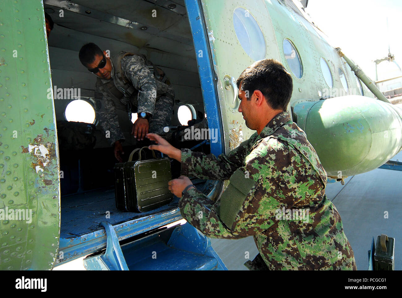 Kandahar, Afghanistan - l'aviation de l'Armée nationale afghane (ANAAC) armurier, Habibur Rahman, droit, les mains d'un cas de munitions de Sgt. 1re classe David Lara, un conseiller médical aero avec le 738e Corps expéditionnaire aérien Advisory Group, une unité de formation de la puissance aérienne de la force combinée de Transition (CAPTF), avant une mission médicale à bord d'un hélicoptère ANAAC M-17. CAPTF est l'élément d'une formation à la capacité de l'air de Mission de formation en Afghanistan (NTM-A), dont le siège social est situé sur le Camp Eggers à Kaboul. La NTM-A Les équipes de soutien régional de faciliter la formation et de conseiller l'armée afghane, la police et l'Armée de l'air afghane tout au long Banque D'Images