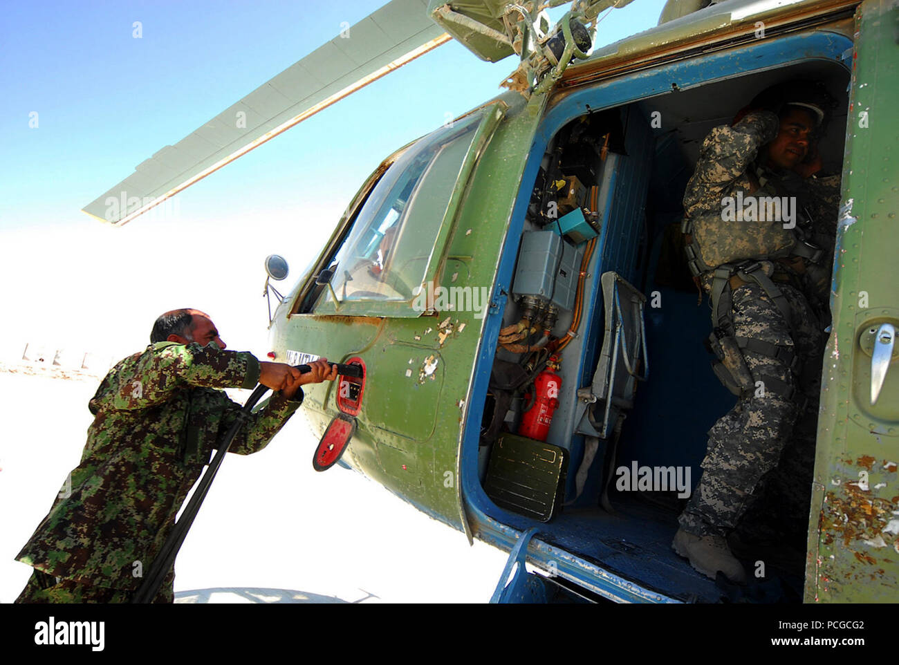 Kandahar, Afghanistan - l'aviation de l'Armée nationale afghane (ANAAC) membre de l'équipage au sol, Ahmad Shah, gauche, prépare une ANAAC M-17 hélicoptère pour une mission médicale en branchant une source d'alimentation externe, comme le Sgt. 1re classe David Lara, un conseiller médical aero avec le 738e Corps expéditionnaire aérien Advisory Group, une unité de formation de la puissance aérienne de la force combinée de Transition (CAPTF), met son équipement après l'arrimage d'armes et de munitions. CAPTF est l'élément d'une formation à la capacité de l'air de Mission de formation en Afghanistan (NTM-A), dont le siège social est situé sur le Camp Eggers à Kaboul. La NTM-A Les équipes de soutien régional de faciliter la formation d'un Banque D'Images