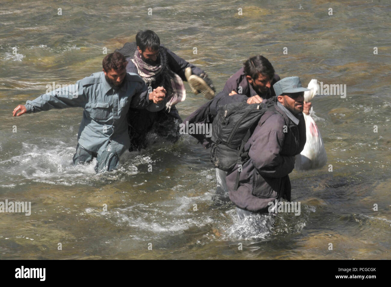 Les troupes de la Police nationale afghane patauger dans l'eau à hauteur de genoux d'atteindre que des hélicoptères Mi-17 pour se rendre dans leur maison dans le cadre d'une mission de ravitaillement de combat en barge Matal dans le nord de la vallée de la Kunar, 10 mars. L'Afghan Air Force a travaillé en coopération avec le ministère de l'intérieur et les forces de la coalition pour terminer la mission, à l'aide de dix avions pour offrir plus de 9 000 kilogrammes d'armes, de munitions et de vivres à la Police nationale afghane stationnée dans le poste distant qui est considérée comme essentielle par les responsables afghans en raison de sa proximité avec le Pakistan et l'histoire de l'activité des insurgés. 1200x190x14 prix Banque D'Images