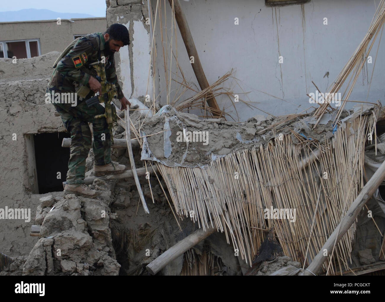 Une armée nationale afghane soldat des forces spéciales recherche les caches d'armes le 21 février 2014, dans un immeuble abandonné au cours d'une opération de compensation de perturber les activités des insurgés dans Muhammad Agah district, province de Logar, en Afghanistan. Avec la police locale afghane, les soldats ANASF trouvé trois caches d'armes et explosifs, y compris environ 100 kilogrammes d'explosifs attachée pour l'exploser. Banque D'Images