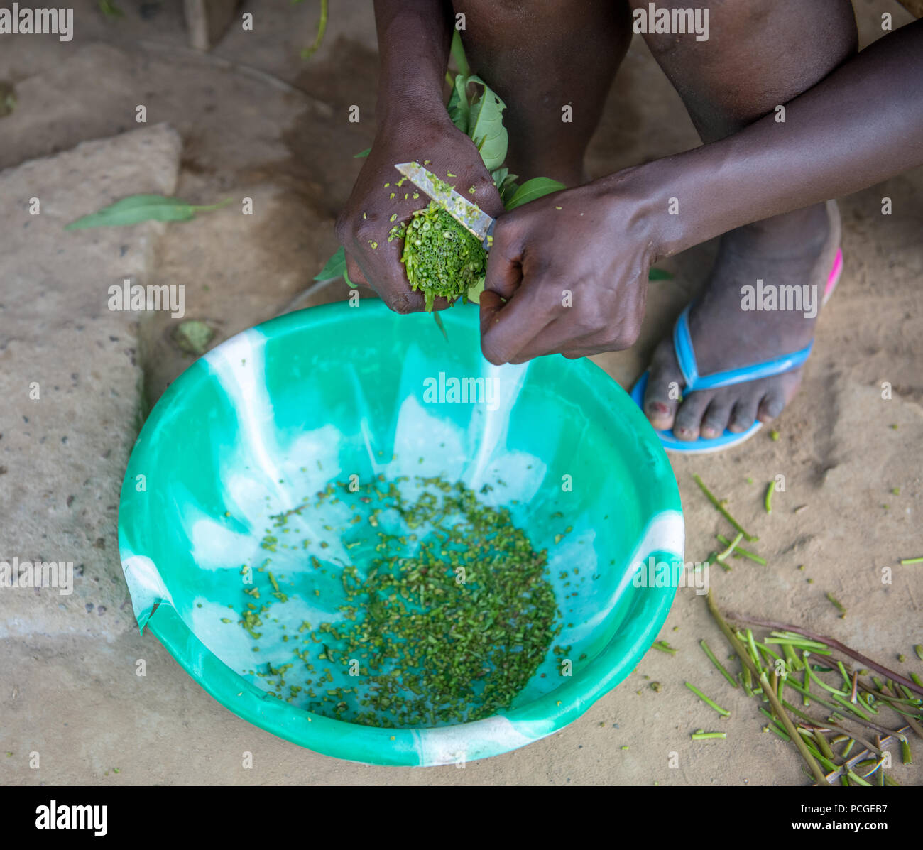 Les greens sont haché dans un bol en préparation d'un repas au Ganta, au Libéria Banque D'Images